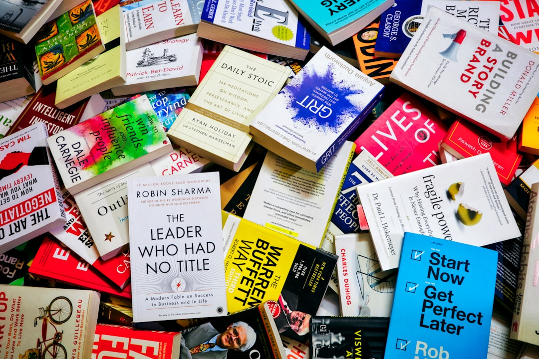 Colorful assortment of business and self-help books spread out on a table, highlighting diverse cover designs, fonts, and styles.