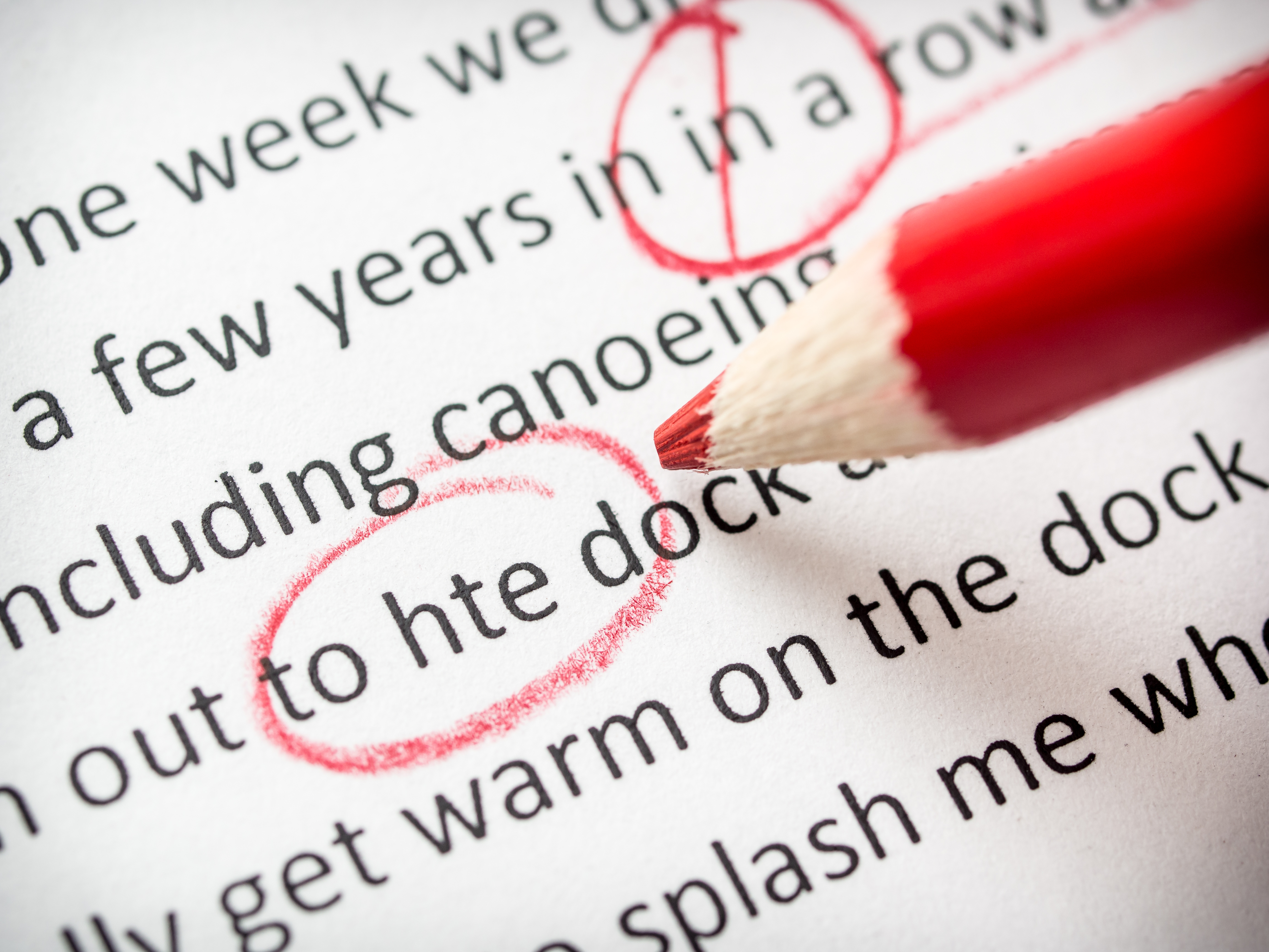 Close-up of a red pencil circling a typo in printed text, highlighting the importance of professional book editing.